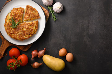 Spanish omelette with potatoes and onion and ingredient Spanish cuisine. Tortilla espanola. Rustic dark background. Flat lay
