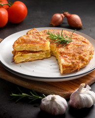 Spanish omelette with potatoes and onion and ingredient Spanish cuisine. Tortilla espanola. Rustic dark background
