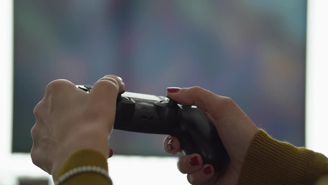 Female gamer hands game controller television in background.