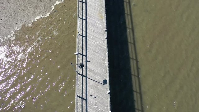 A top down shot, taken directly over a wooden pier in Little Neck Bay, Queens, NY. The camera slowly moves forward while tilting down. It was shot at low tide on a bright & sunny day.