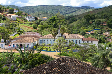 View in a valley with colonial buildings and mountains covered with lush green Atlantic forest in Serro, Minas Gerais, Brazil