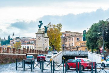 Rome, Italy. Vehicular traffic on cobblestone streets of the city. Statues of angels with wreaths...