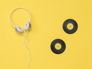 White headphones and yellow vinyl discs on a yellow background.