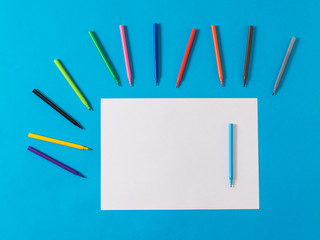 A white sheet of paper and a set of markers on a blue background.