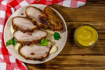 Baked pork belly in a plate on wooden table. Top view
