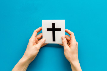 Catholic cross sign in hands - catholicism religion concept - on blue background top view copy space
