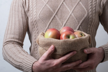 Man holds a cloth bag with apples. Bag of burlap with village apples in the hands of a man.