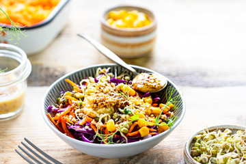 Vegetable salad of fresh red cabbage with carrots, onions, corn, mung seedlings in a plate on wooden background. Selective focus. Copy space. horizontal