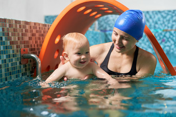 Very interesting active training in swimming pool. Little cute boy is learning how to float with his supportive mother. Concept of healthy family