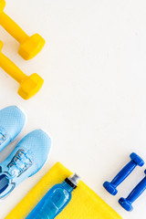 Fitness set with sneakers, dumbbells, towel on white background top view copy space