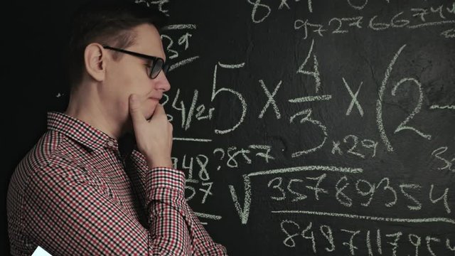 man writes math formula on blackboard