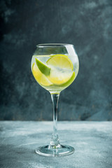 Rum based cocktail with lime in wine glass (variation of cuba libre) on the rustic background. Selective focus. Shallow depth of field.