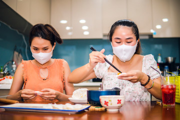 two young women cooking the tapioca dumpling in quarantine for coronavirus wearing protective mask during covid-19 pandemic 