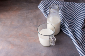 Fresh milk in a glass cup and a bottle with a beautiful towel on the table.