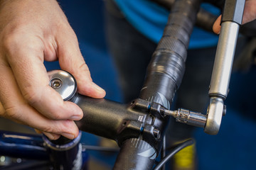 Tightening of a bicycle handlebar stem with the use of a small torque wrench. Proper way to tighten a bicycle handlebars. Bicycle service in a worshop. - obrazy, fototapety, plakaty