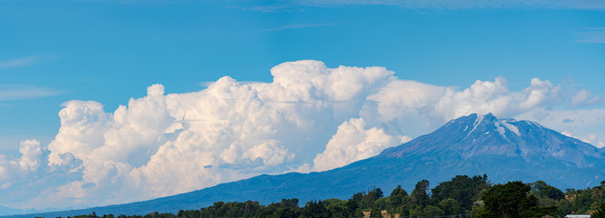 large formation clouds next to the top of calbuco volcano on a sunny day