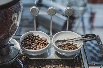 Coffee beans in a white ceramic bowls. Coffee beans on a display for tasting. Selection of coffee beans in a coffee factory.
