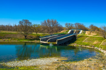 Water flows from a concrete spillway into a pond. Hydraulic structures for water discharge