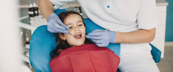Caucasian girl with opened mouth having a dental examination at the pediatric dentist