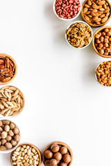 Nuts set in bowls on white background top-down frame copy space