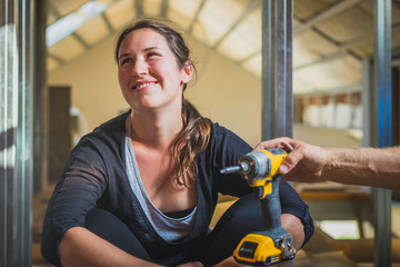 Young cute caucasian woman with black hair is being offered a work tool and she is kindly refusing it. Woman refusing to work with home tools.