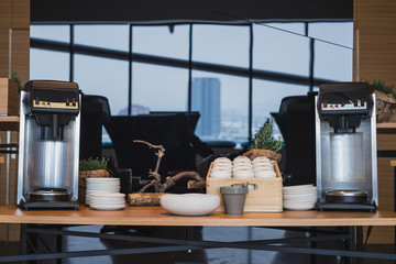 Frontal view of two coffee machines on a desk used for coffee break on an event or a meeting. Coffee time on a seminar - table with machines ready to serve coffee.