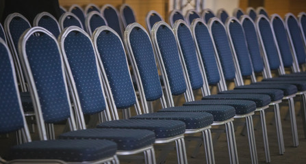 Fototapeta premium Row of blue chairs with white dots and aluminium frame on a conference or a meeting. Row of modern blue chairs in a conference hall.