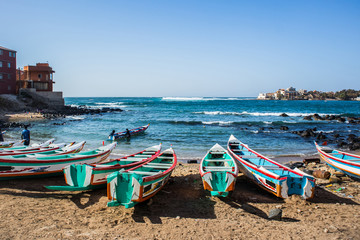 Fishing boats in Ngor Dakar, Senegal, called pirogue or piragua or piraga. Colorful boats used by fishermen standing in the bay of Ngor on a sunny day. - obrazy, fototapety, plakaty