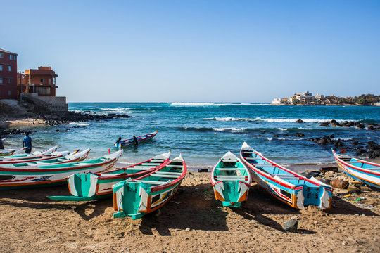 Naklejki Fishing boats in Ngor Dakar, Senegal, called pirogue or piragua or piraga. Colorful boats used by fishermen standing in the bay of Ngor on a sunny day.