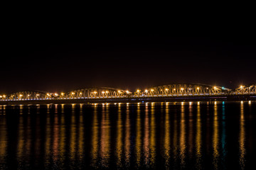 Faidherbe bridge, a metal bridge spaning over the river in Sant Louis, Senegal in late night with a cars and some people passing over it.