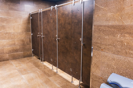 Public toilet restroom with brown doors in a row.
