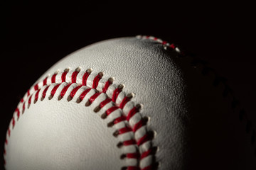 A white leather baseball on a black background - 338684965