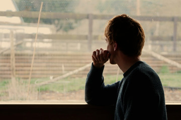 Silhouette of man gazing out of window