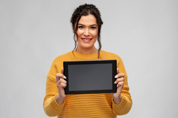 technology and people concept - happy woman showing tablet computer over grey background