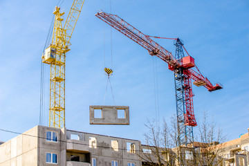 Two construction cranes against the blue sky
