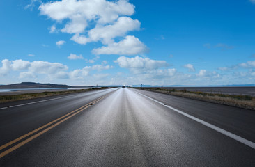 Autostrada verso l'orizzonte con cielo azzurro e qualche nuvola