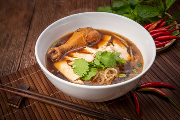 Chicken noodle soup on wood table, Chicken soup with noodles and vegetables in bowl over rustic wooden background