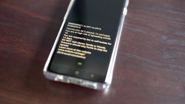 Emergency Alert Message Received In A Smartphone For Travellers Returning To Ontario, Canada To Self-Isolate Themselves To Prevent Spreading Of COVID-19 - Closeup Shot