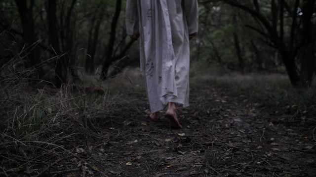 Dramatic shot of Jesus walking in slow motion through forest trees