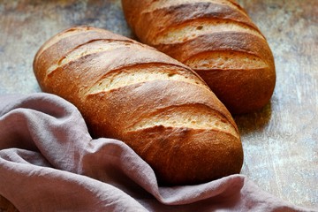 Fresh loaf on a brown background.  Traditional wheat freshly rustic baked bread, loaf of bread.