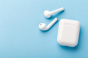 Fototapeta na wymiar Modern wireless bluetooth headphones with charging case on a blue background.