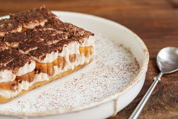 Tiramisu. Traditional italian dessert on wooden background. Garnished with a sprig of mint, lime slices. In a transparent cup, tea with sea buckthorn.