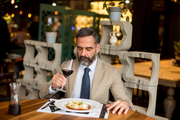 Handsome mature man drinking red wine during lunch