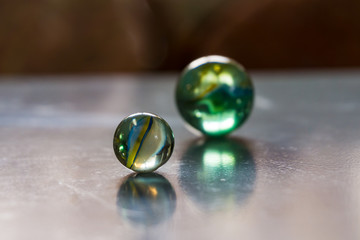 Two decorative colored glass balls with bubbles inside reflecting in icy surface. Concept of similarity, design elements.