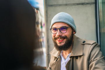 Smiling hipster man sitting with female friend in cafe
