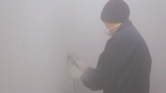 Worker removing surface cover from the wall