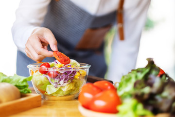 Closeup image of a female chef cooking a fresh mixed vegetables salad in kitchen