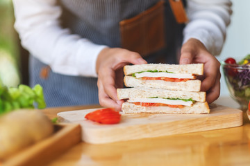 Closeup image of a female chef cooking and holding a piece of whole wheat sandwich in kitchen