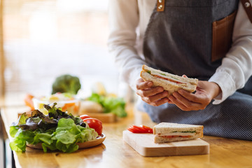 Closeup image of a female chef cooking and hloding a whole wheat sandwich in kitchen