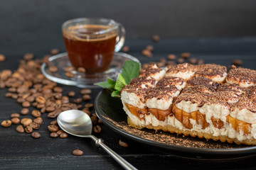 Tiramisu. Traditional italian dessert on wooden background. Garnished with a sprig of mint, lime slices. In the background are drinks. Coffee, masala tea with spices.